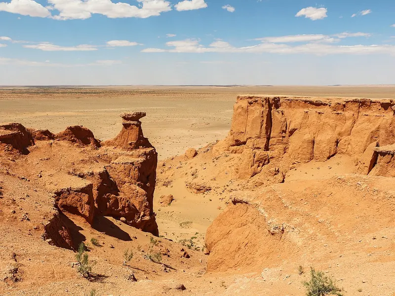 Red and orange sandstone cliffs and gullies in a dry desert landscape